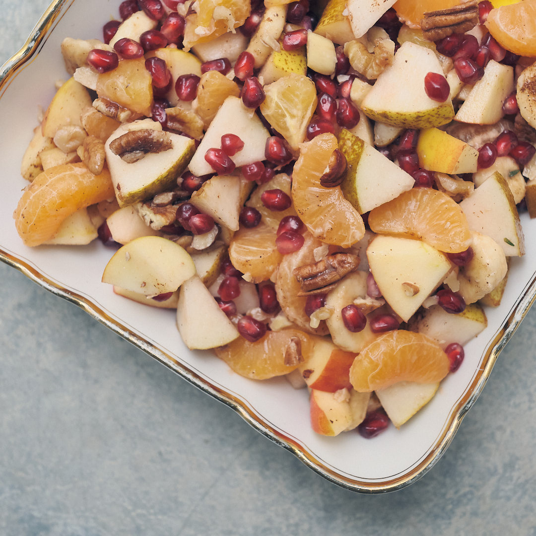 Fruit salad with clementines, banana, pear, apple, pomegranate seeds and nuts